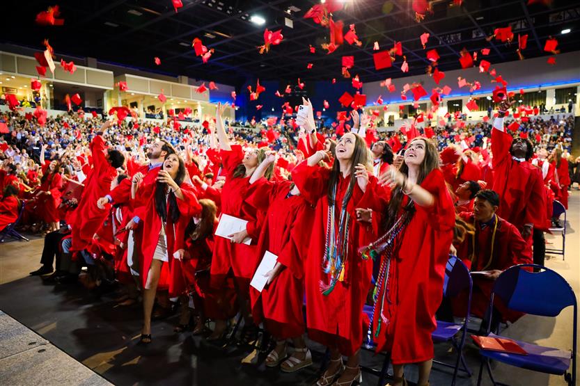 Students in red robes graduate